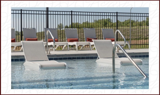 pool with reclining seats and lush landscaping